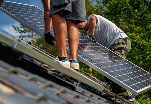 Deux installateurs de panneaux solaires photovoltaïques sur le toit d'une maison